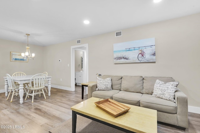 living room with light hardwood / wood-style floors and a notable chandelier