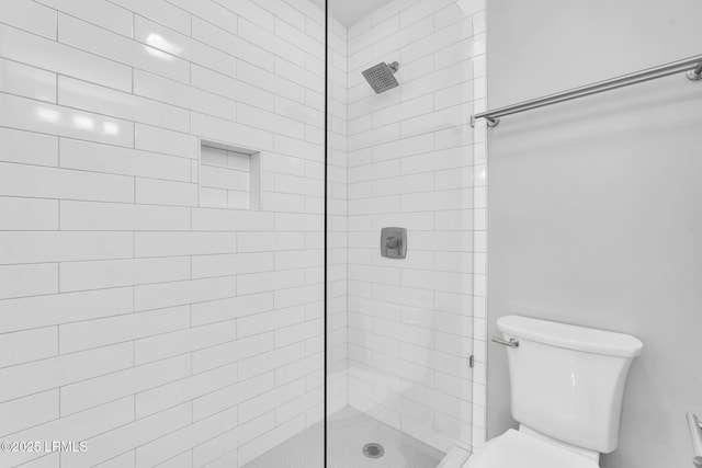 bathroom with a tile shower and toilet