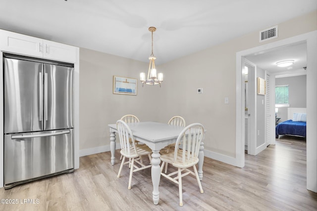 dining space with a chandelier and light wood-type flooring