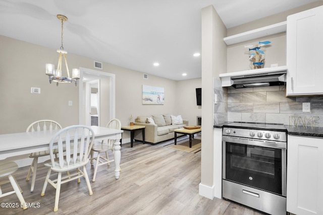 kitchen featuring stainless steel range with electric cooktop, white cabinetry, light wood-type flooring, pendant lighting, and backsplash