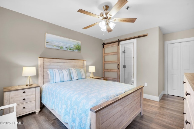 bedroom with dark hardwood / wood-style flooring, a barn door, and ceiling fan