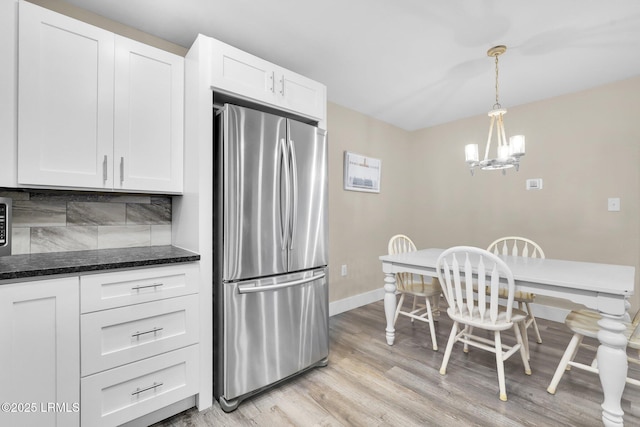 kitchen featuring tasteful backsplash, white cabinetry, stainless steel fridge, and hanging light fixtures