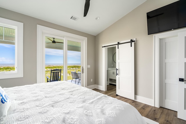 bedroom featuring a barn door, access to exterior, lofted ceiling, wood finished floors, and baseboards