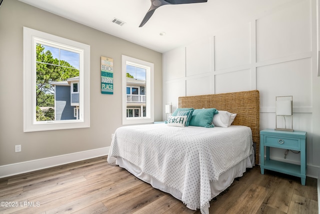 bedroom with multiple windows, wood finished floors, and baseboards