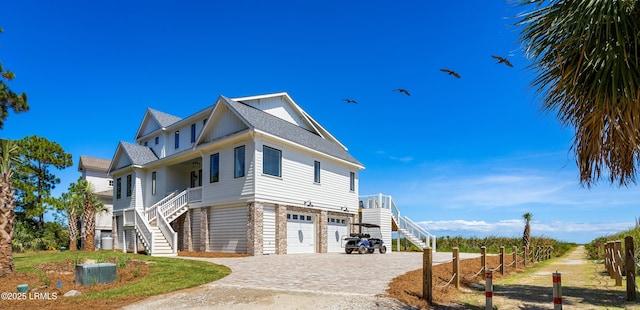 view of front facade featuring stairs, a garage, driveway, and a porch