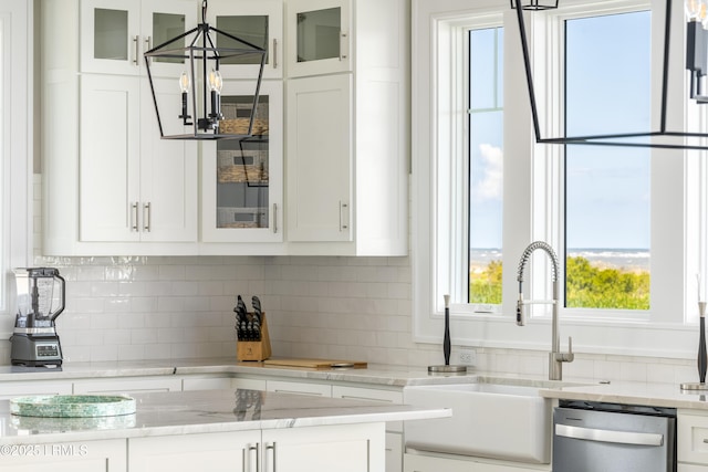 kitchen featuring dishwasher, white cabinetry, a chandelier, a sink, and backsplash