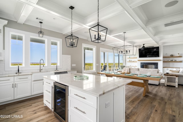 kitchen featuring wine cooler, a sink, wood finished floors, coffered ceiling, and a kitchen island