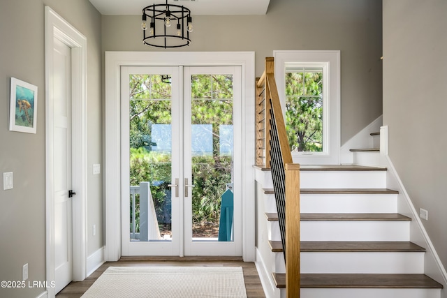 doorway featuring stairway, healthy amount of natural light, wood finished floors, and french doors