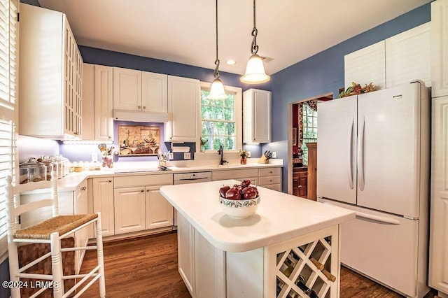 kitchen featuring dark wood-type flooring, white cabinetry, a center island, white fridge, and pendant lighting