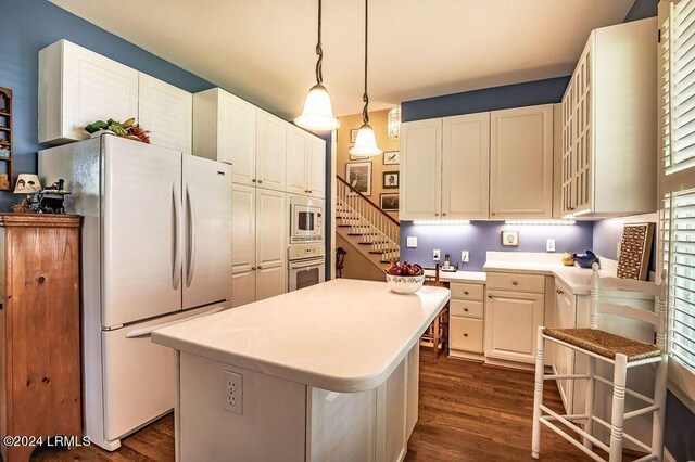 kitchen featuring built in microwave, white cabinetry, a center island, white refrigerator, and pendant lighting