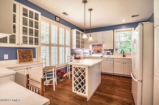 kitchen with sink, decorative light fixtures, a center island, dark hardwood / wood-style flooring, and white appliances