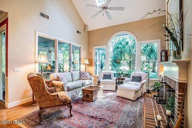 sunroom featuring ceiling fan, lofted ceiling, and a brick fireplace