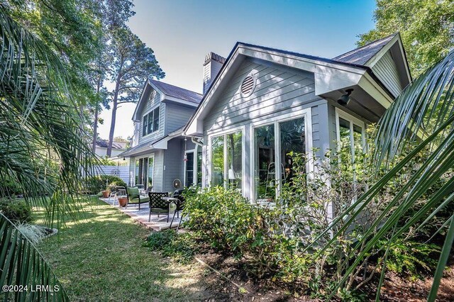 back of property featuring a patio area and a lawn