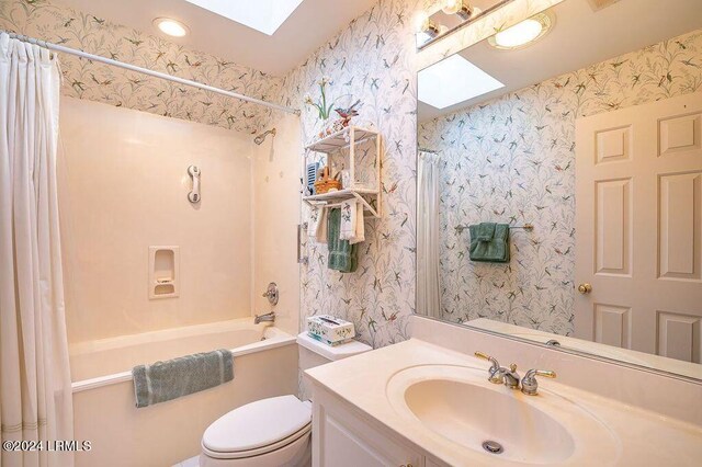 full bathroom featuring shower / tub combo with curtain, vanity, toilet, and a skylight