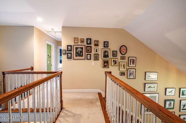 hallway featuring lofted ceiling and light colored carpet