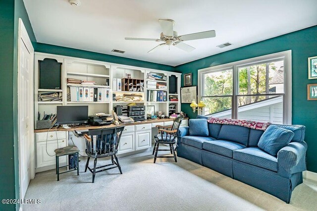 carpeted office featuring ceiling fan and built in desk