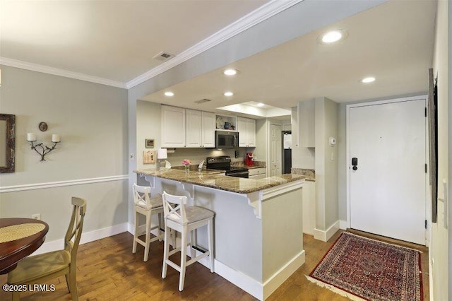 13 Harbourside Ln Unit 7155, Hilton Head Island, SC 29928 - kitchen featuring ornamental molding, black range with electric cooktop, stainless steel microwave, a breakfast bar area, and wood finished floors