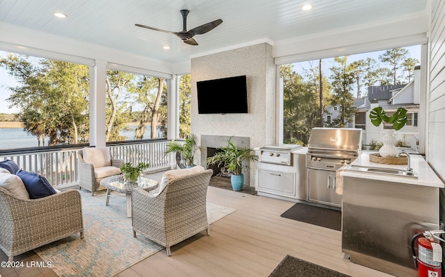 sunroom with sink, plenty of natural light, a large fireplace, and a water view