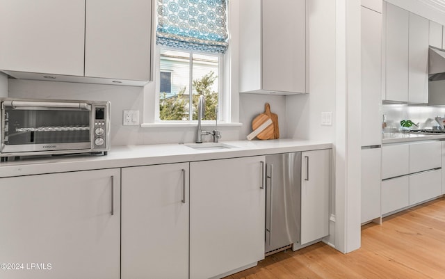 kitchen featuring white cabinetry, sink, and light wood-type flooring