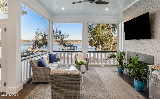 sunroom with a water view and ceiling fan