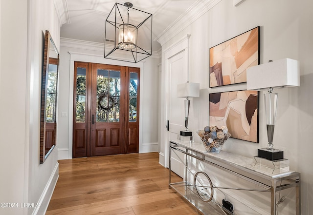 foyer with crown molding, an inviting chandelier, and light wood-type flooring