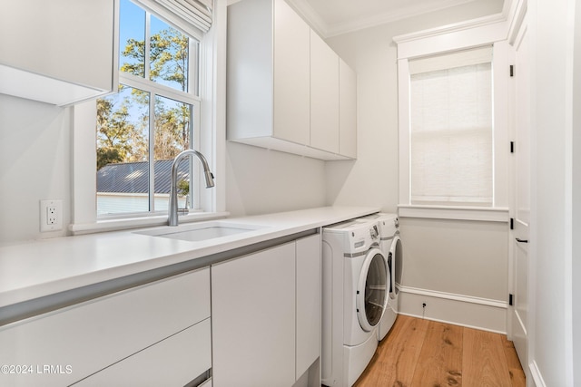 laundry area with separate washer and dryer, sink, cabinets, ornamental molding, and light hardwood / wood-style floors