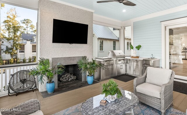 view of patio featuring sink, area for grilling, a wooden deck, ceiling fan, and exterior kitchen