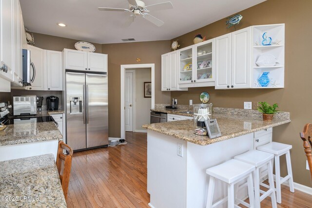 kitchen featuring stainless steel appliances, kitchen peninsula, and white cabinets