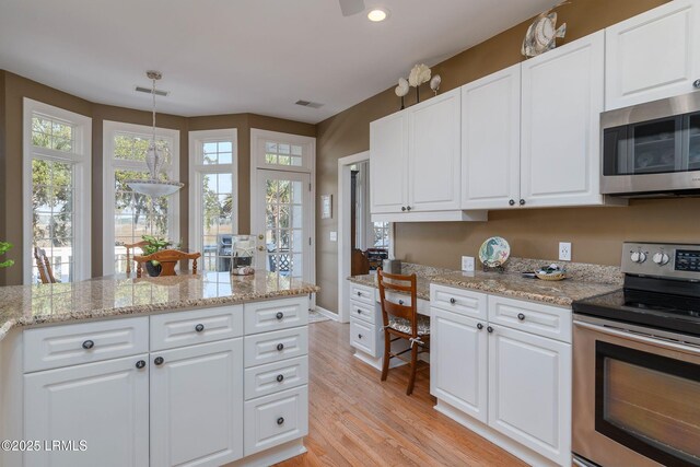 kitchen featuring white cabinetry, hanging light fixtures, stainless steel appliances, light stone countertops, and light wood-type flooring