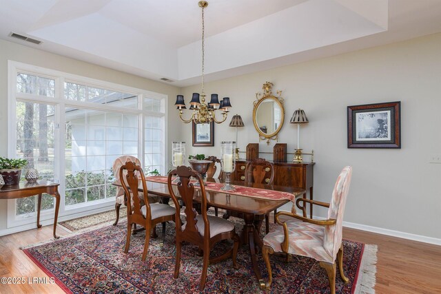 dining room featuring hardwood / wood-style floors, a notable chandelier, and a tray ceiling