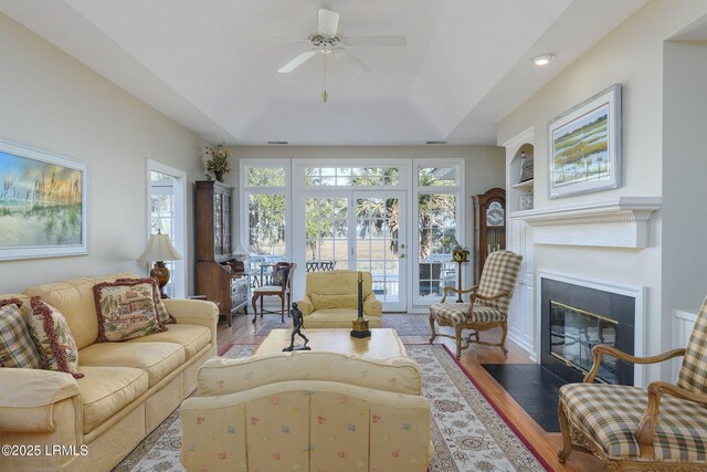 living room with hardwood / wood-style floors, ceiling fan, and a tray ceiling