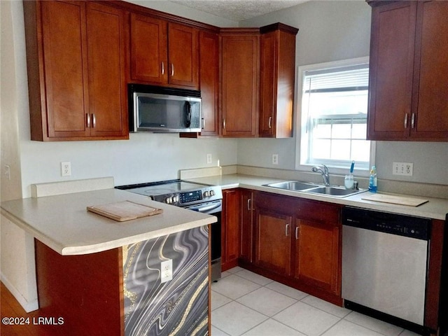 kitchen with appliances with stainless steel finishes, sink, a kitchen bar, light tile patterned floors, and kitchen peninsula