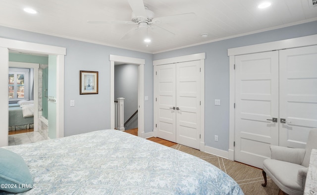 bedroom with ornamental molding, two closets, ceiling fan, and light hardwood / wood-style flooring