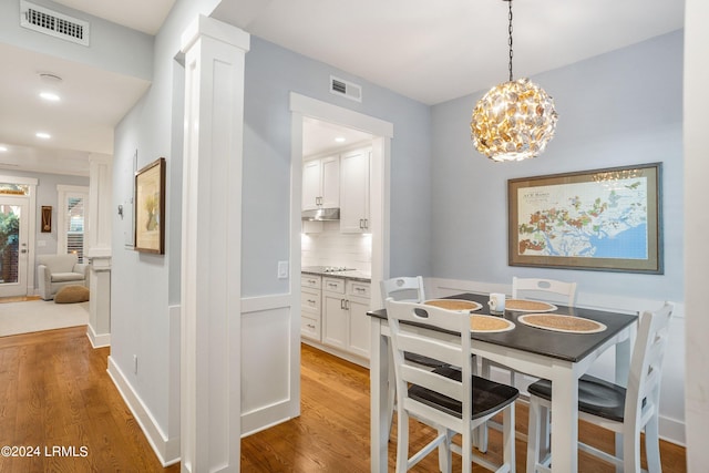 dining room with hardwood / wood-style flooring and ornate columns