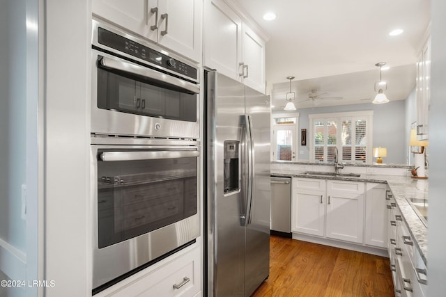 kitchen with stainless steel appliances, kitchen peninsula, sink, and white cabinets