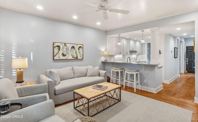 living room with decorative columns, sink, ceiling fan, wood ceiling, and light wood-type flooring