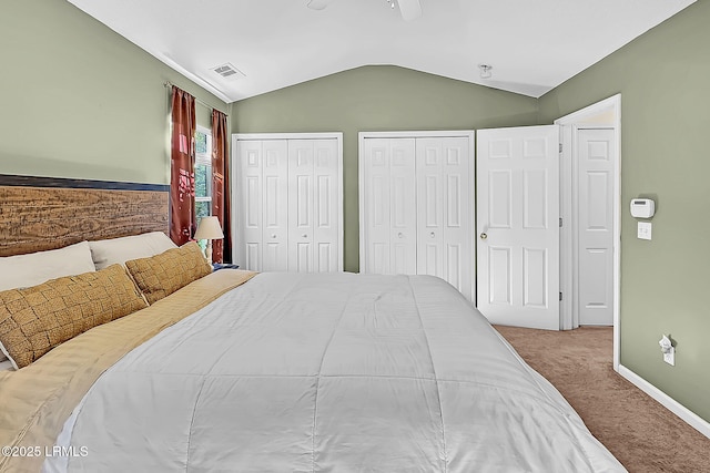 bedroom featuring lofted ceiling, two closets, ceiling fan, and carpet flooring