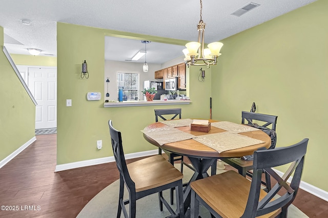 dining room with an inviting chandelier, hardwood / wood-style floors, and a textured ceiling