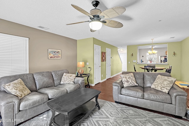 living room featuring hardwood / wood-style flooring, ceiling fan with notable chandelier, and a textured ceiling