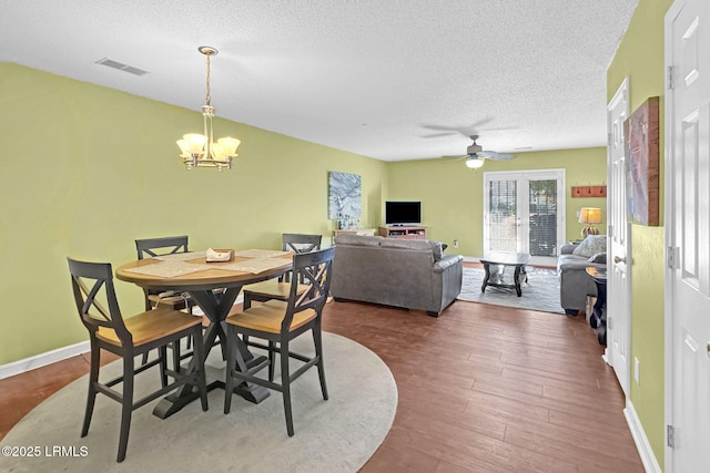 dining area featuring hardwood / wood-style flooring, ceiling fan with notable chandelier, and a textured ceiling