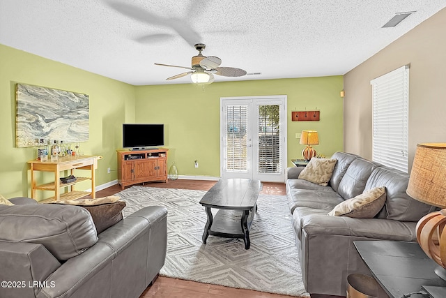 tiled living room featuring a textured ceiling, french doors, and ceiling fan