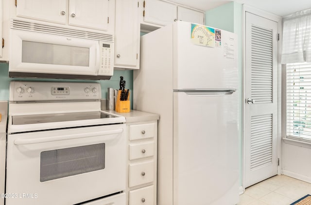 kitchen with light tile patterned floors, white cabinets, and white appliances