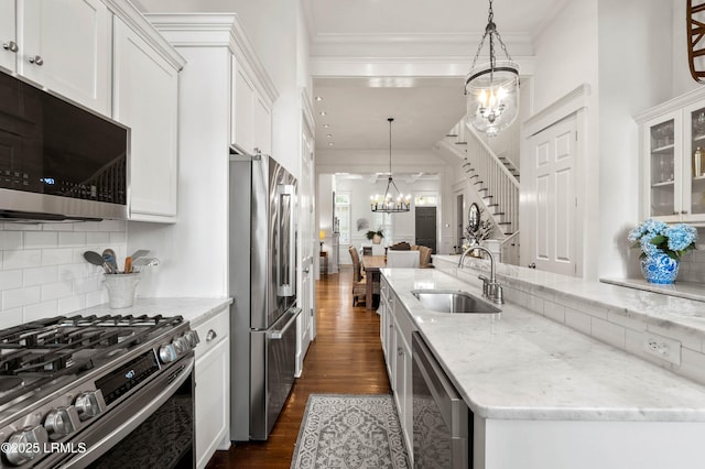 kitchen with dark wood-style floors, backsplash, an inviting chandelier, appliances with stainless steel finishes, and a sink