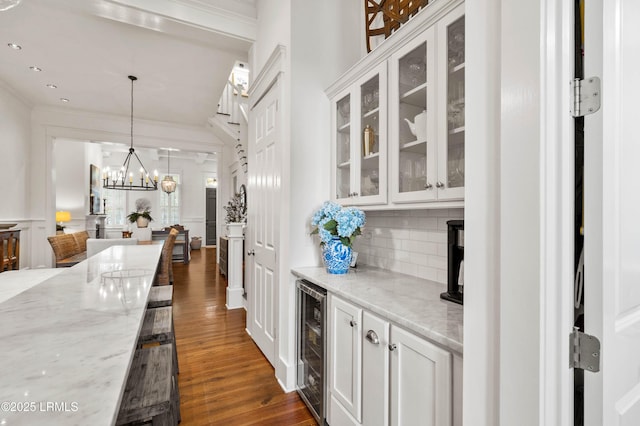 kitchen featuring dark wood finished floors, decorative backsplash, wine cooler, light stone countertops, and white cabinetry