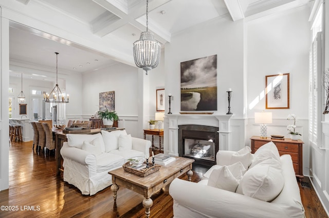 living room with crown molding, a fireplace, wood finished floors, a chandelier, and beamed ceiling