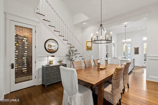 dining room with a chandelier, a decorative wall, stairway, and wood finished floors