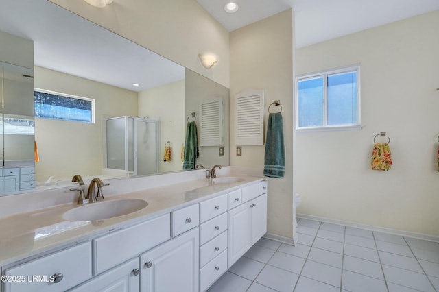 bathroom with double vanity, baseboards, a stall shower, and a sink