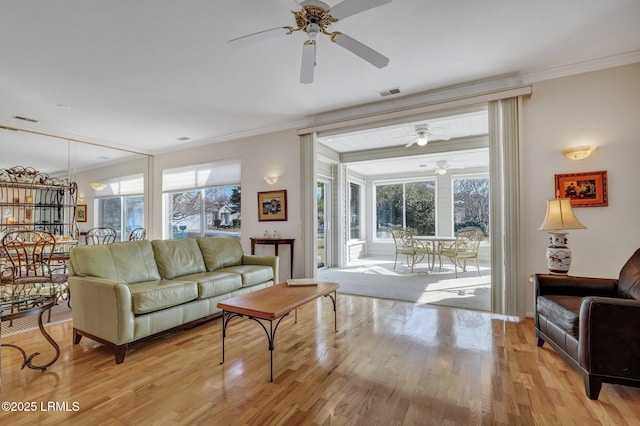 living area featuring visible vents, crown molding, and light wood-style floors