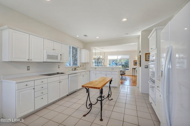 kitchen featuring a sink, white appliances, a peninsula, and a wealth of natural light