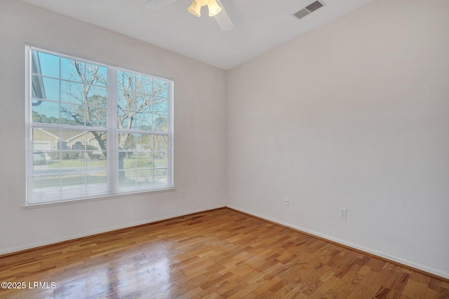 unfurnished room with baseboards, light wood-style floors, visible vents, and ceiling fan